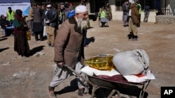  ایک معمر افغان انسانی ہمدردی کی امداد کے ایک مرکز سے ایک ریڑھی پر امدادی سامان لے کر جا رہا ہے ، فائل فوٹو 