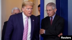 Tổng thống Mỹ Donald Trump đi ngang qua bác sỹ Anthony Fauci, giám đốc Viện Dị ứng và các Bệnh Truyền nhiễm Quốc gia, tại một buổi họp báo của Nhà Trắng để cập nhật tình hình đại dịch COVID-19.