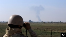 In this Tuesday, Nov. 13, 2018 photo, an Iraqi soldier watches smoke rising after an airstrike by US-led International coalition warplanes against ISIS, on the border between Syria and Iraq in Qaim, Anbar province, Iraq. More than a year after this…